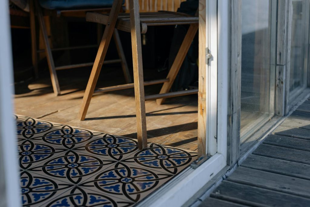 Wooden chair by a decorative tiled floor in a sunlit room, creating a warm, rustic atmosphere.