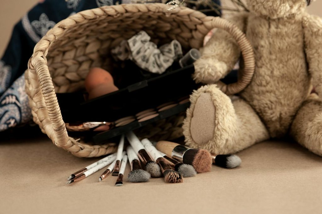 A cozy flat lay featuring makeup brushes and a teddy bear beside a wicker basket.