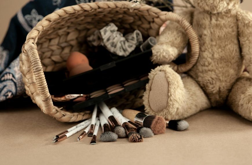 A cozy flat lay featuring makeup brushes and a teddy bear beside a wicker basket.