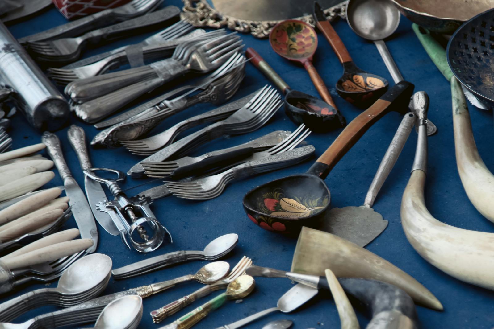 Close-up of assorted vintage cutlery on a blue tablecloth showcasing unique designs.