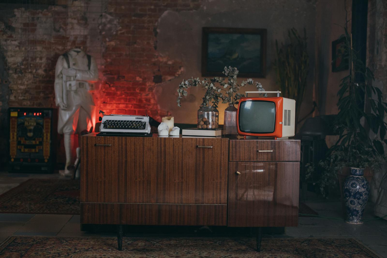 Retro-inspired interior with vintage TV and typewriter on antique cabinet, perfect for classic decor enthusiasts.