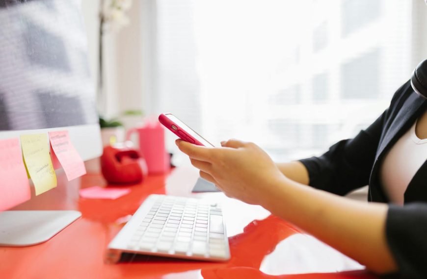 Professional checking mobile phone at modern office workstation.