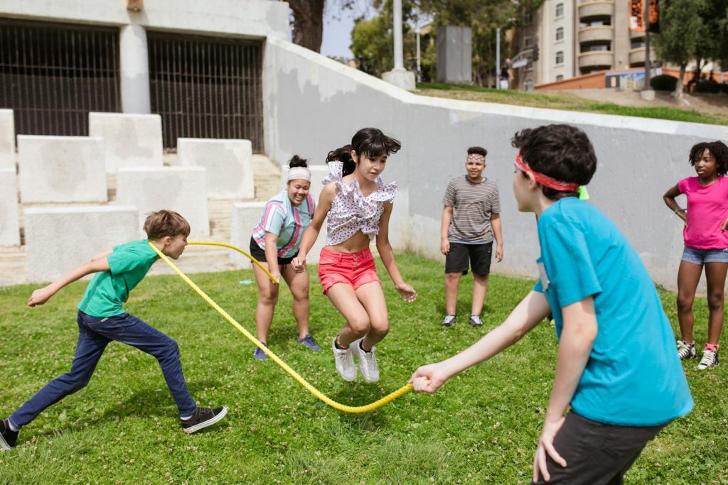Group of kids enjoying a jump rope game outdoors on a sunny day.