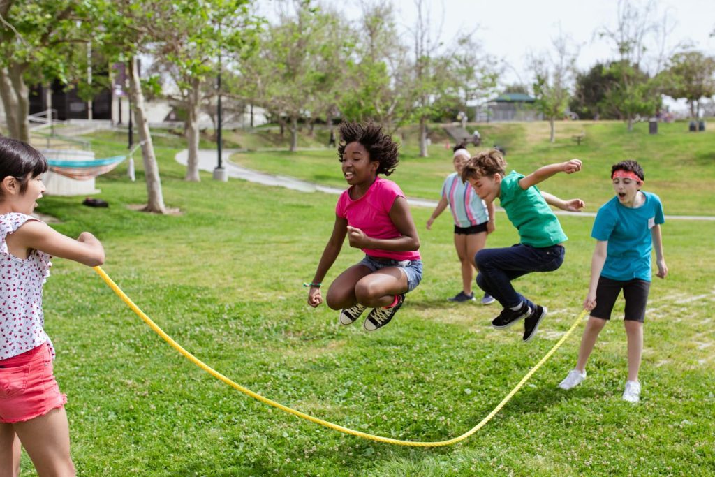 Children enjoying a vibrant day playing jump rope outdoors at summer camp.