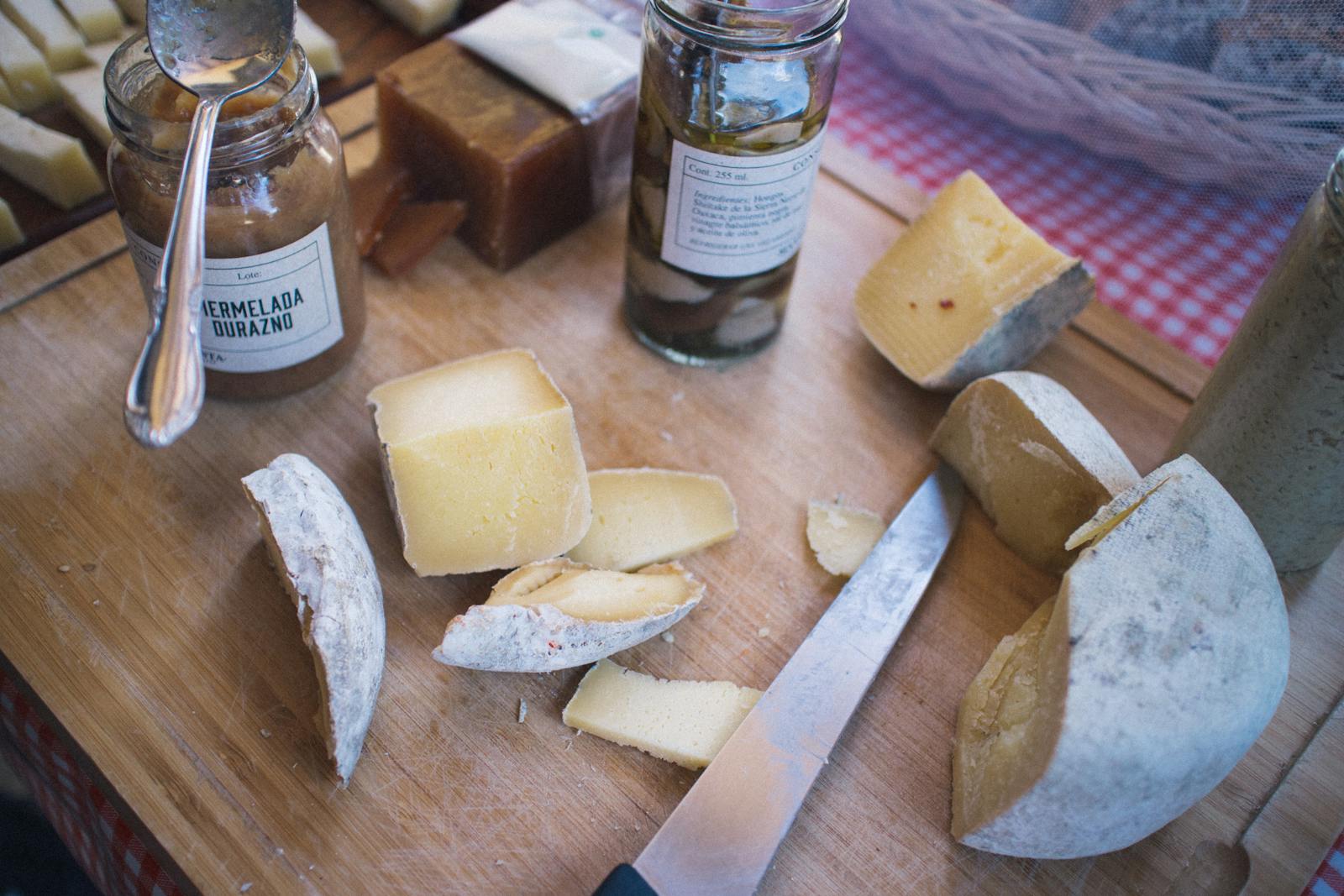 Close-up of assorted cheeses, jam, and knife on a wooden board, creating a rustic culinary scene.