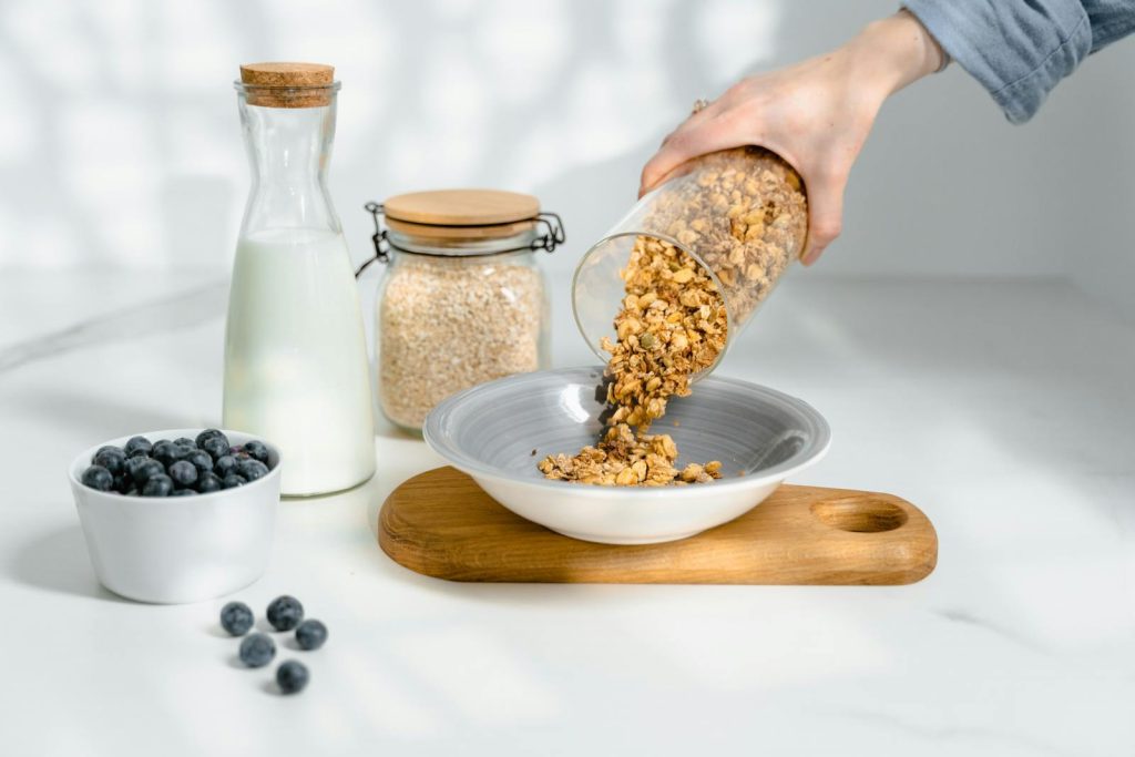 Fresh granola poured into a bowl with milk and blueberries for breakfast.