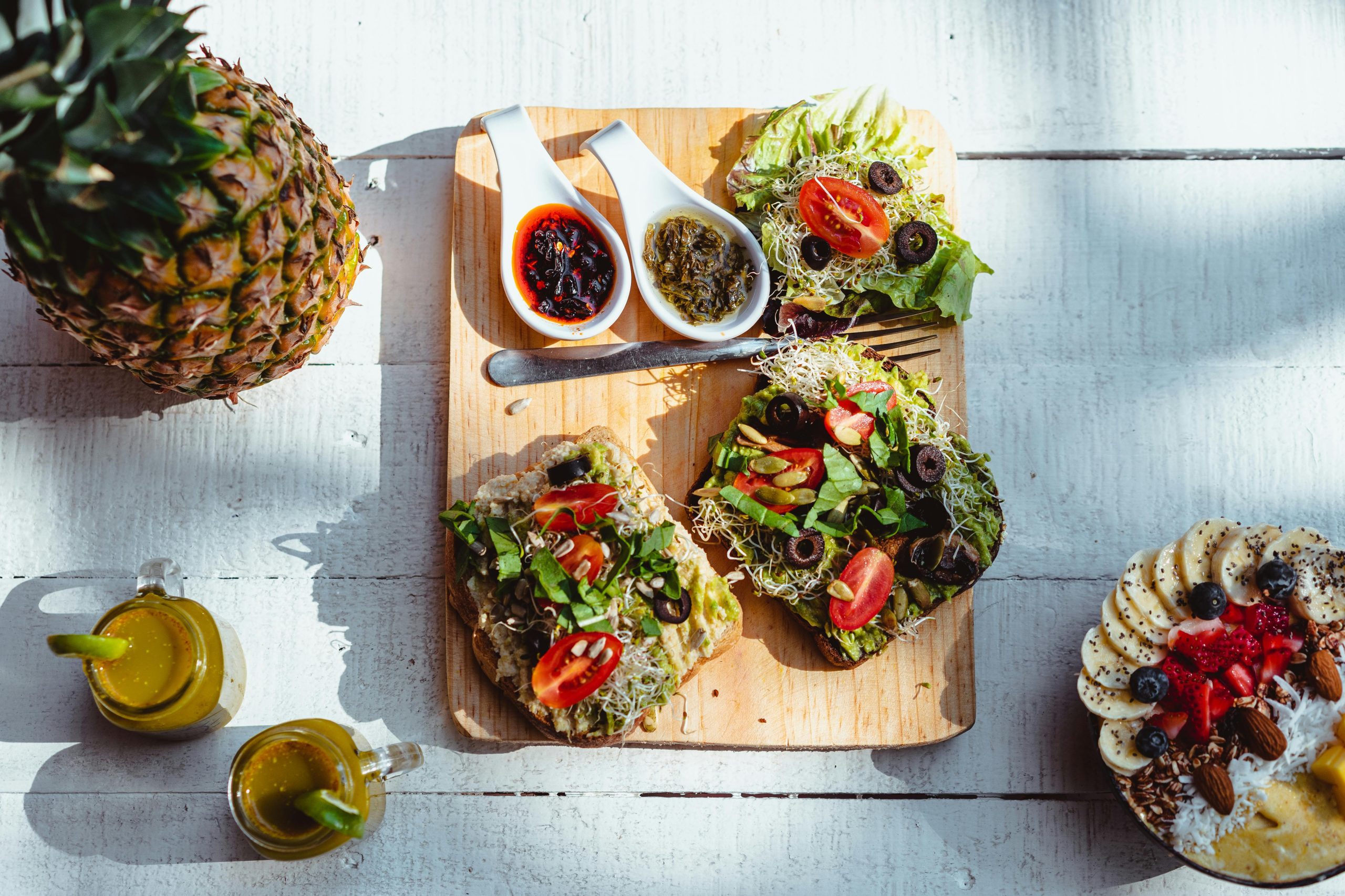 Top view of a vibrant and healthy brunch spread with sandwiches, fruits, and juices on a wooden table.