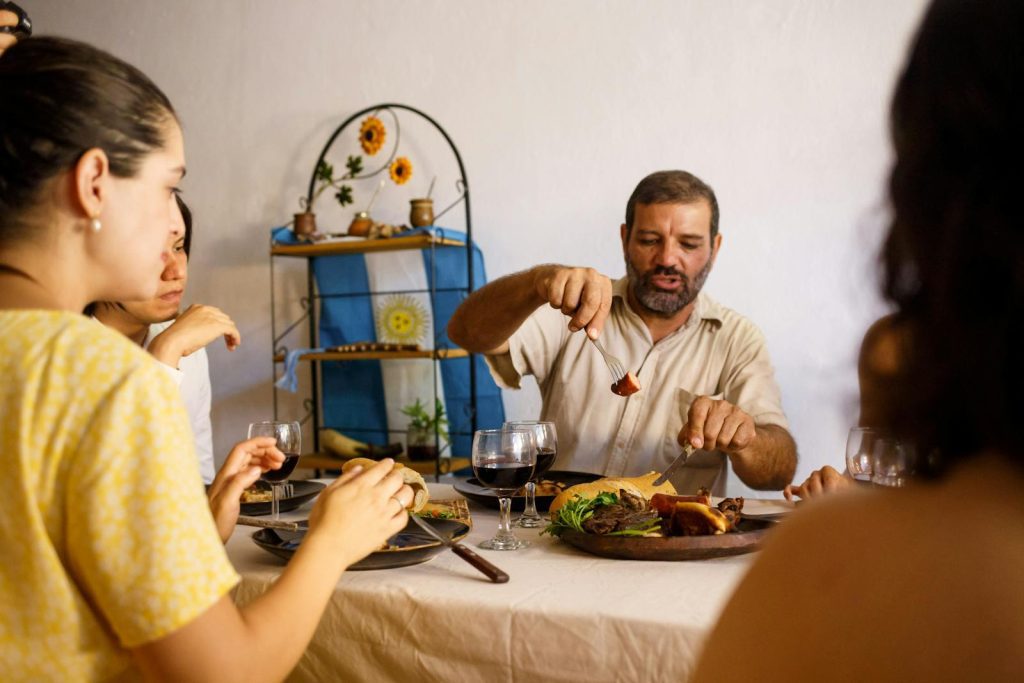 A group of adults sharing a meal with traditional food and wine indoors, enjoying quality time.