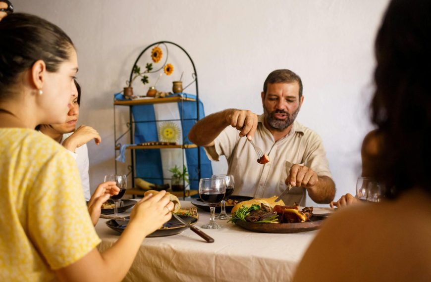 A group of adults sharing a meal with traditional food and wine indoors, enjoying quality time.