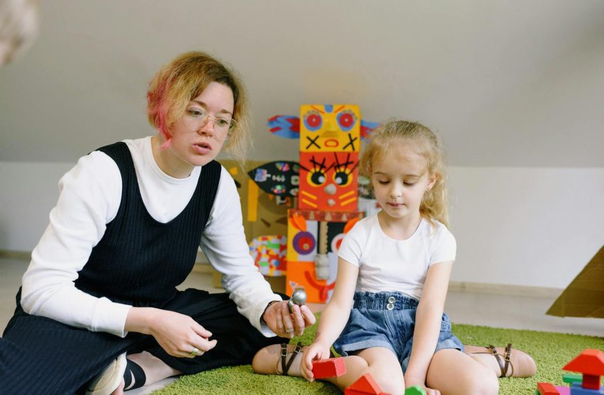 A woman and child playing with colorful wooden blocks in a playroom, creating an imaginative learning experience.