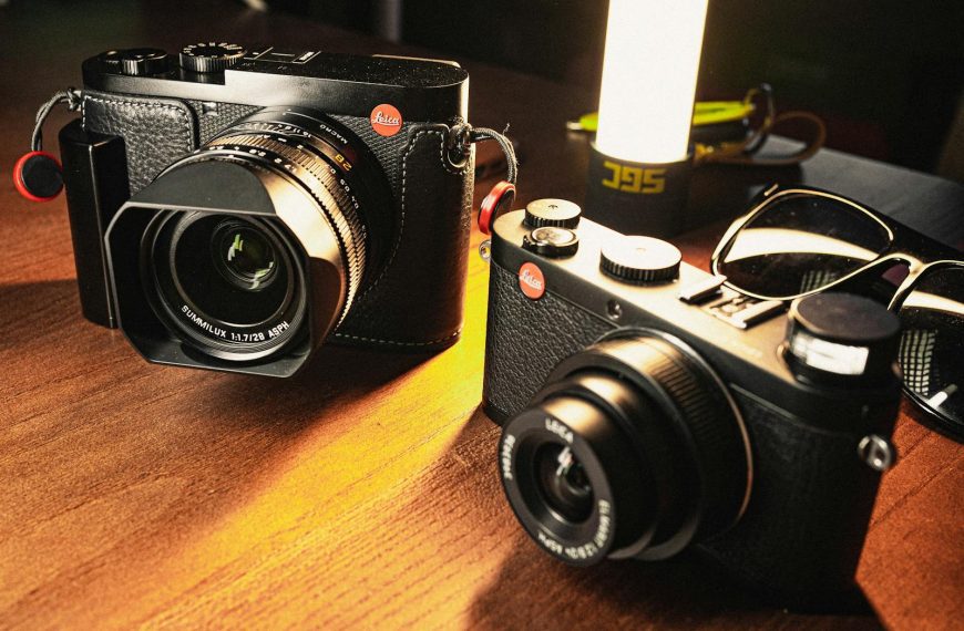 Stylish vintage cameras placed on a wooden table under warm lighting. Ideal for photography enthusiasts.