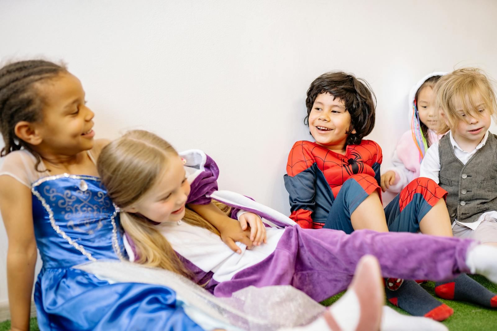 Group of diverse children joyfully playing in colorful costumes indoors.