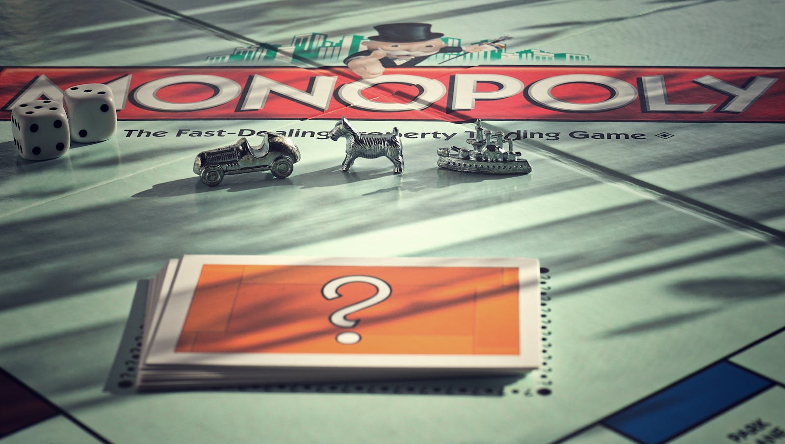 Close-up of Monopoly board game with metal tokens and dice in warm light.