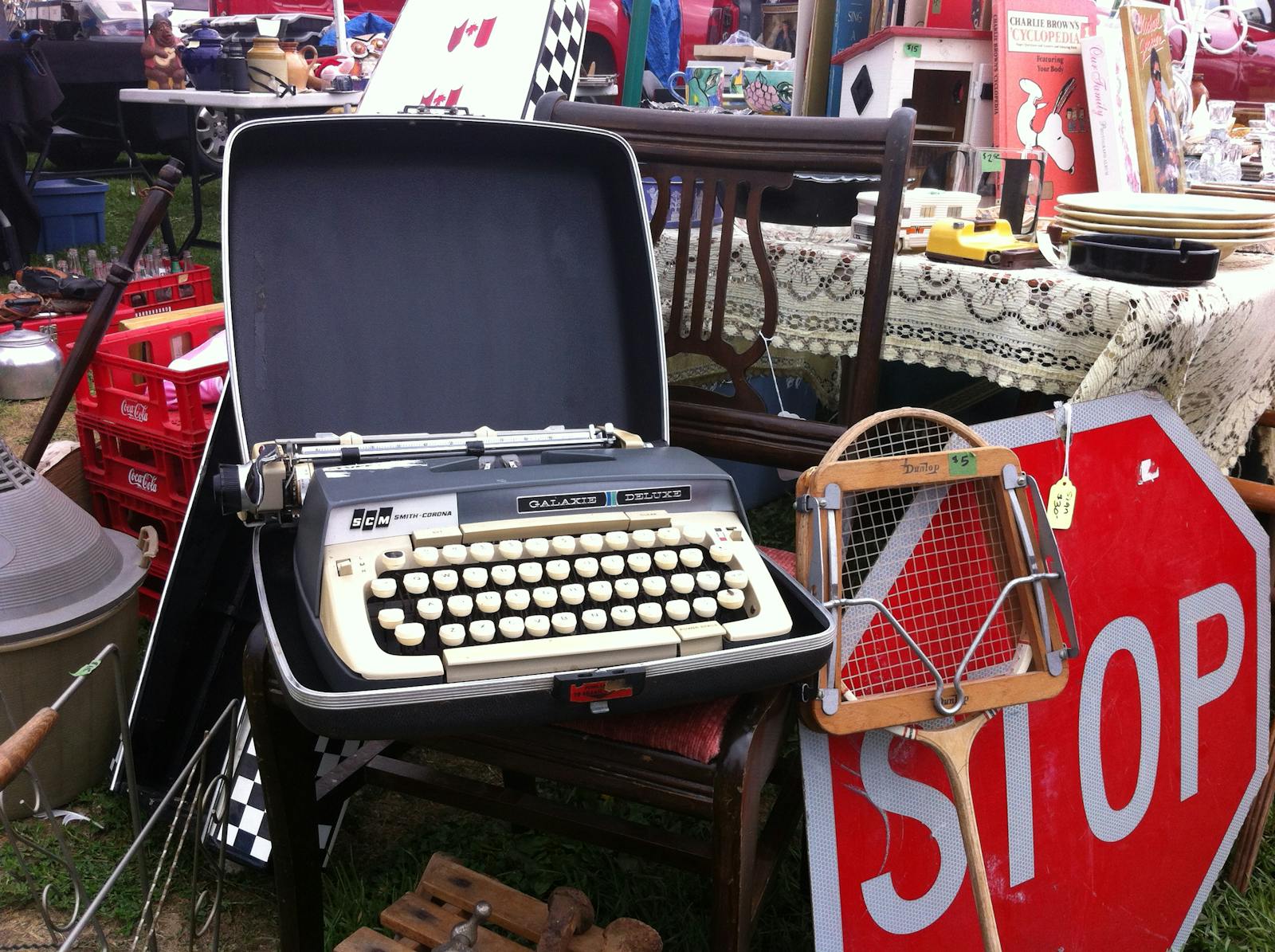 An outdoor flea market featuring a vintage typewriter among various antiques and collectibles.