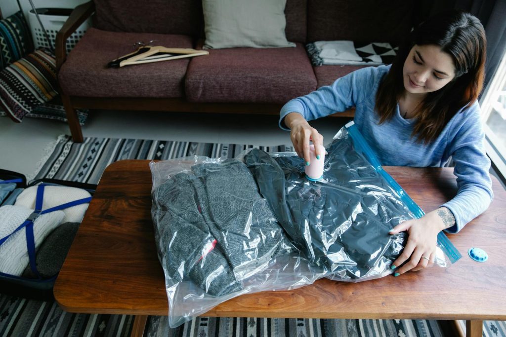 Woman sealing clothes in vacuum bags for efficient packing at home.