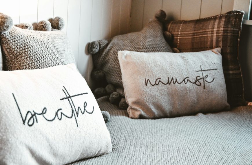 a bed topped with lots of pillows next to a window