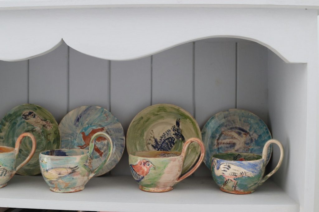 Collection of artistic ceramic cups and saucers on shelf