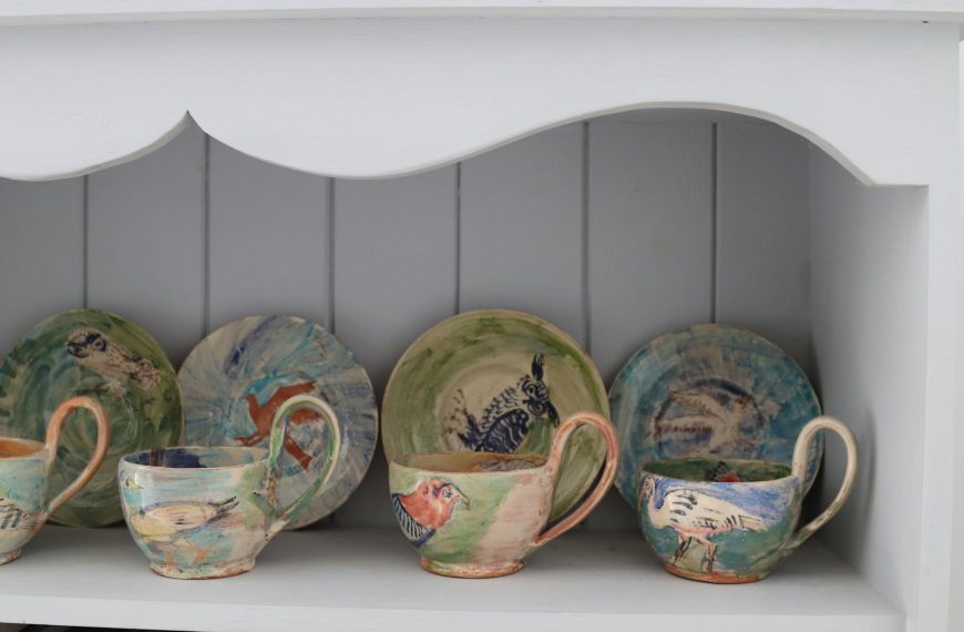 Collection of artistic ceramic cups and saucers on shelf