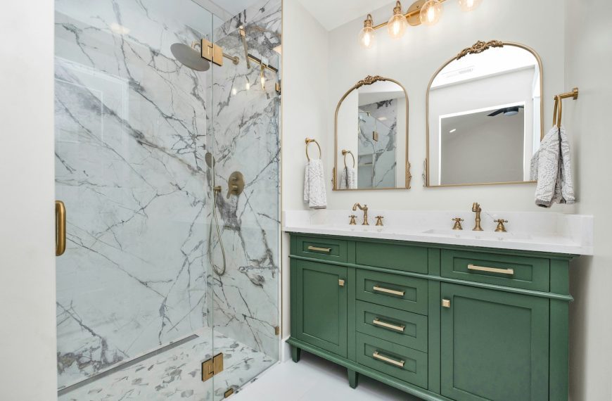 a bathroom with green cabinets and a marble shower
