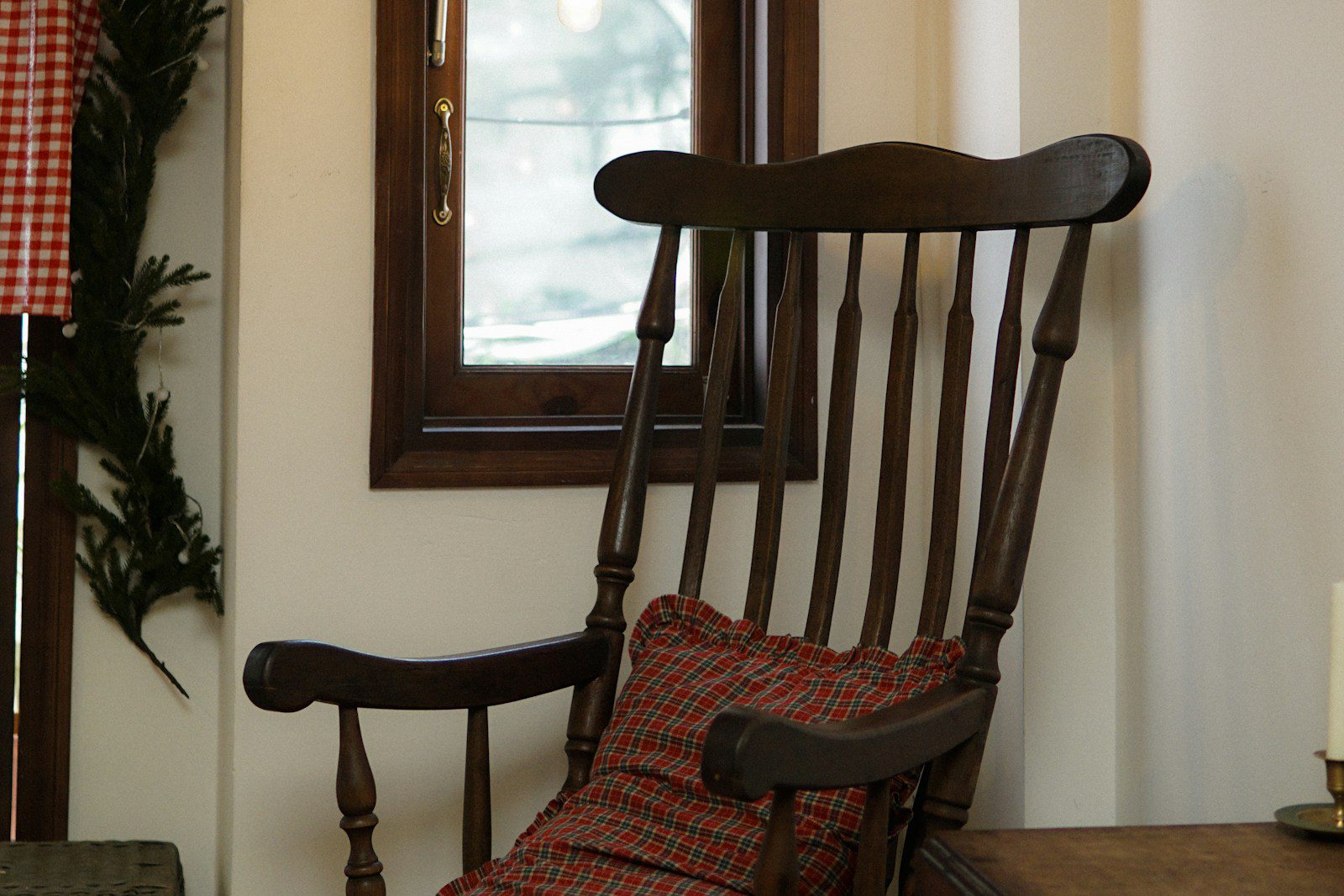 a wooden rocking chair with a plaid pillow on it