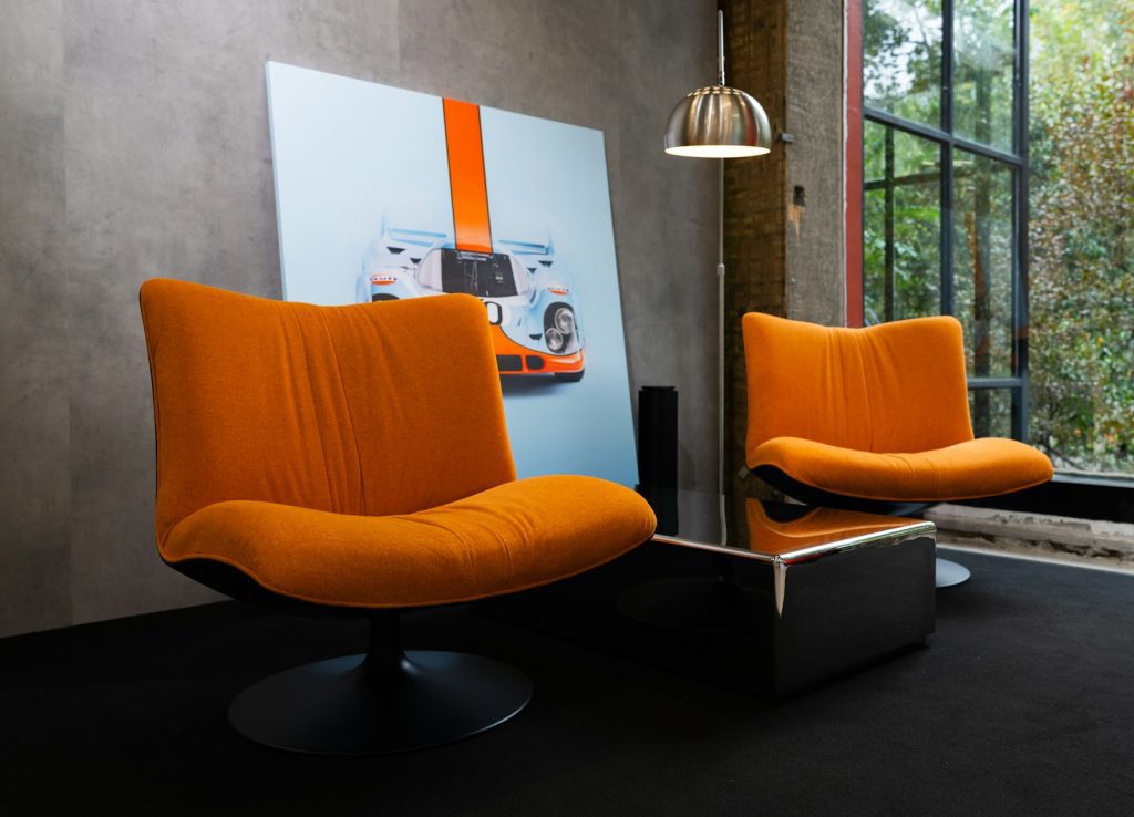 Two orange chairs and a modern coffee table.