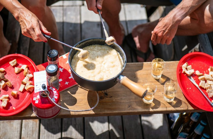 People dipping bread into a cheese fondue pot.