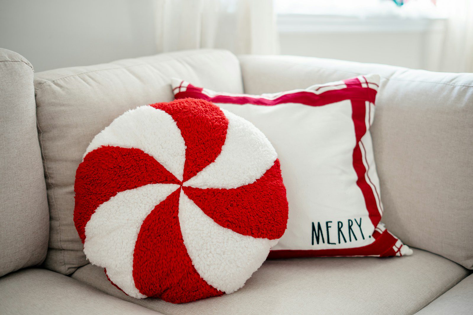 A red and white pillow sitting on top of a white couch