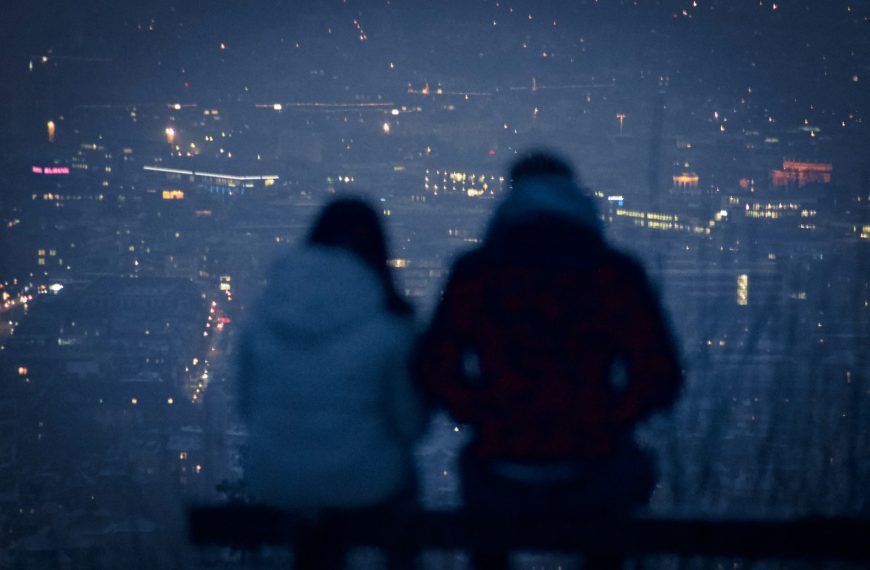 man and woman sitting on bench during night time