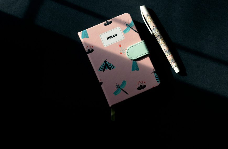 a pink notebook with a pen on top of it