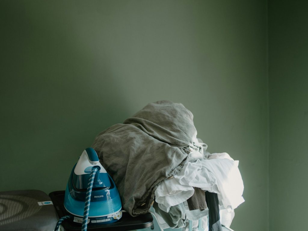 Iron and pile of clothes on ironing board