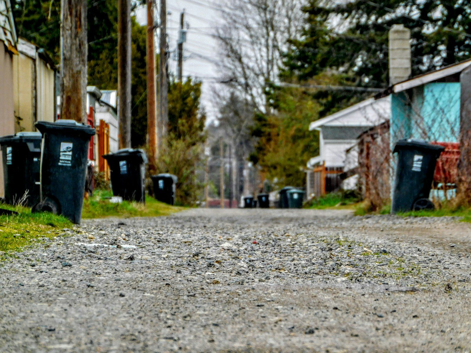 a dirt road with trash cans on the side of it