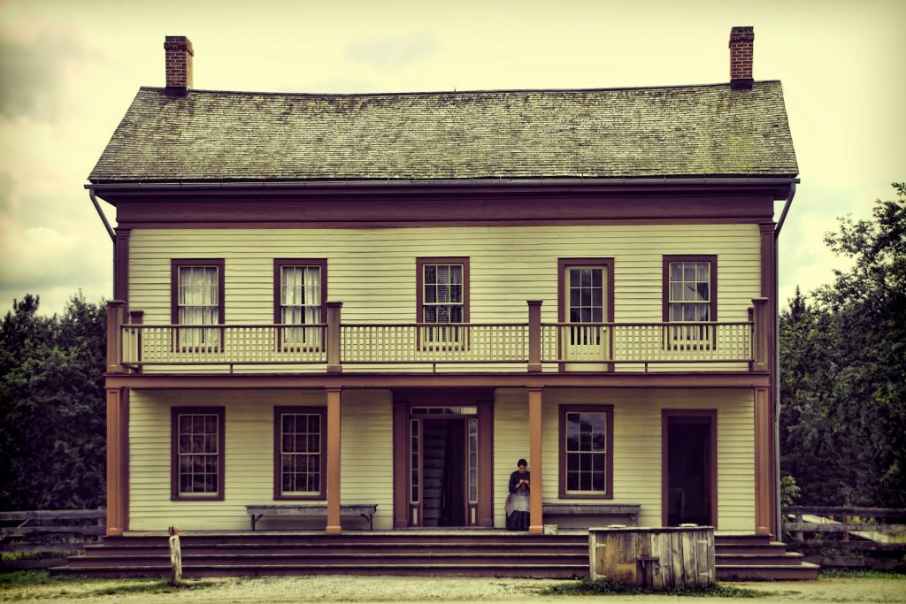 A light yellow two-story house with a balcony