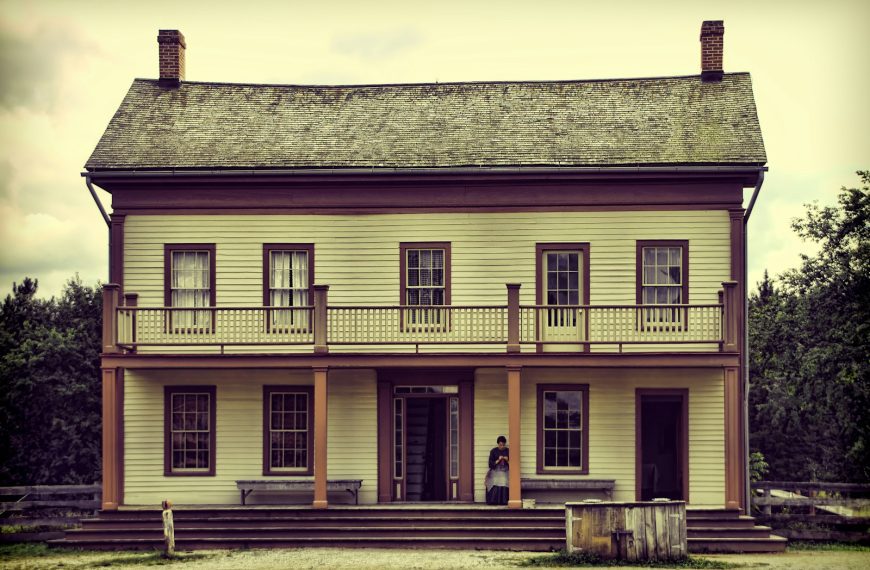 A light yellow two-story house with a balcony