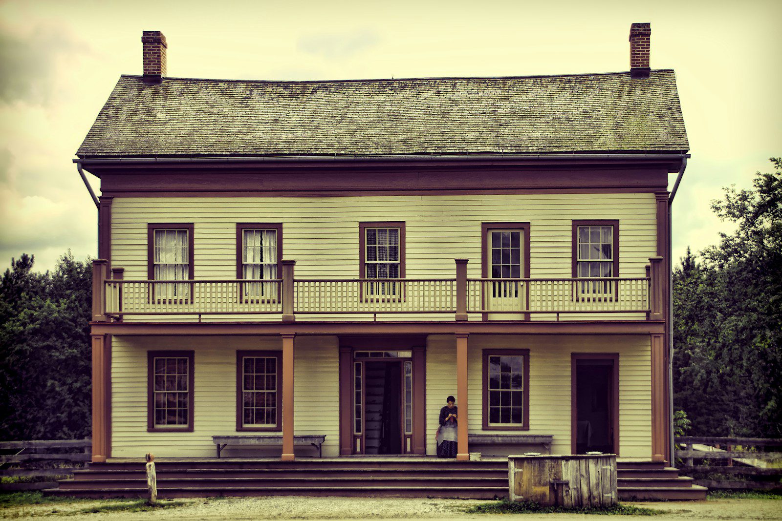 A light yellow two-story house with a balcony