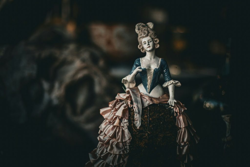 Antique doll with elaborate ruffled dress and hairstyle.