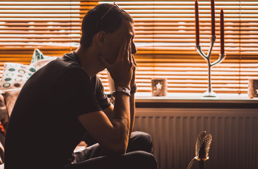 man sitting on chair covering his eyes