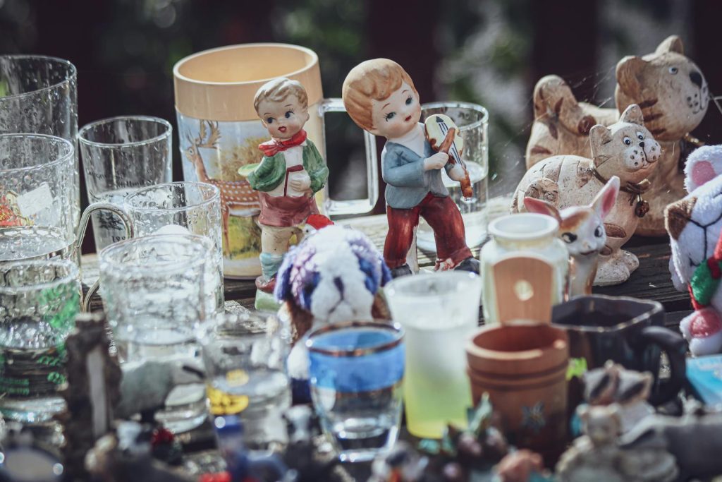 A collection of decorative figurines and glass items displayed on a table at a flea market.