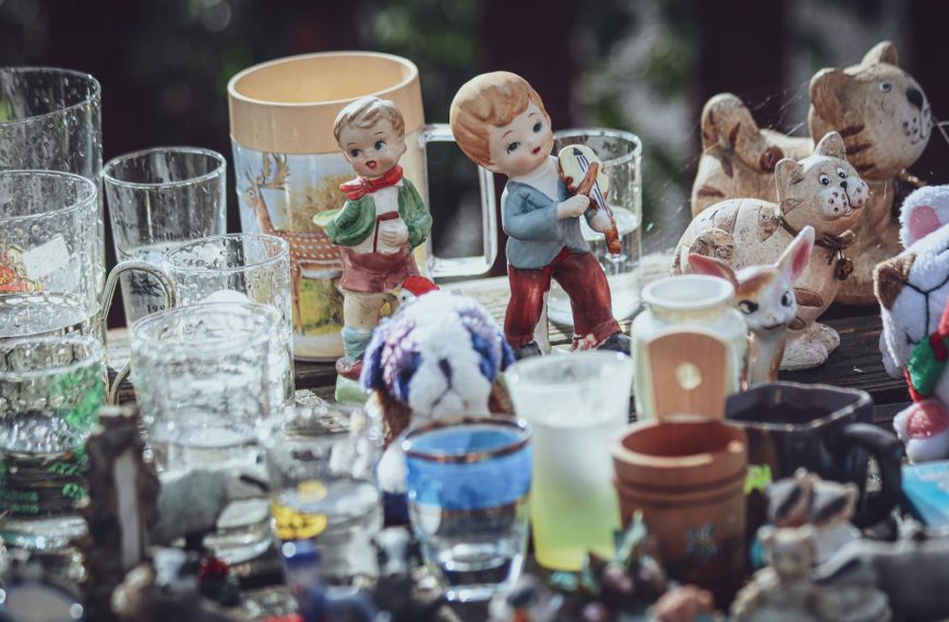 A collection of decorative figurines and glass items displayed on a table at a flea market.