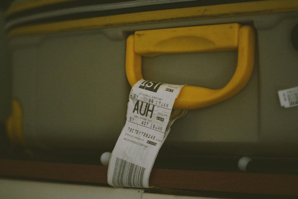 Close-up of a yellow suitcase handle with a visible travel tag and barcode, ideal for travel themes.