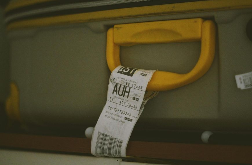 Close-up of a yellow suitcase handle with a visible travel tag and barcode, ideal for travel themes.