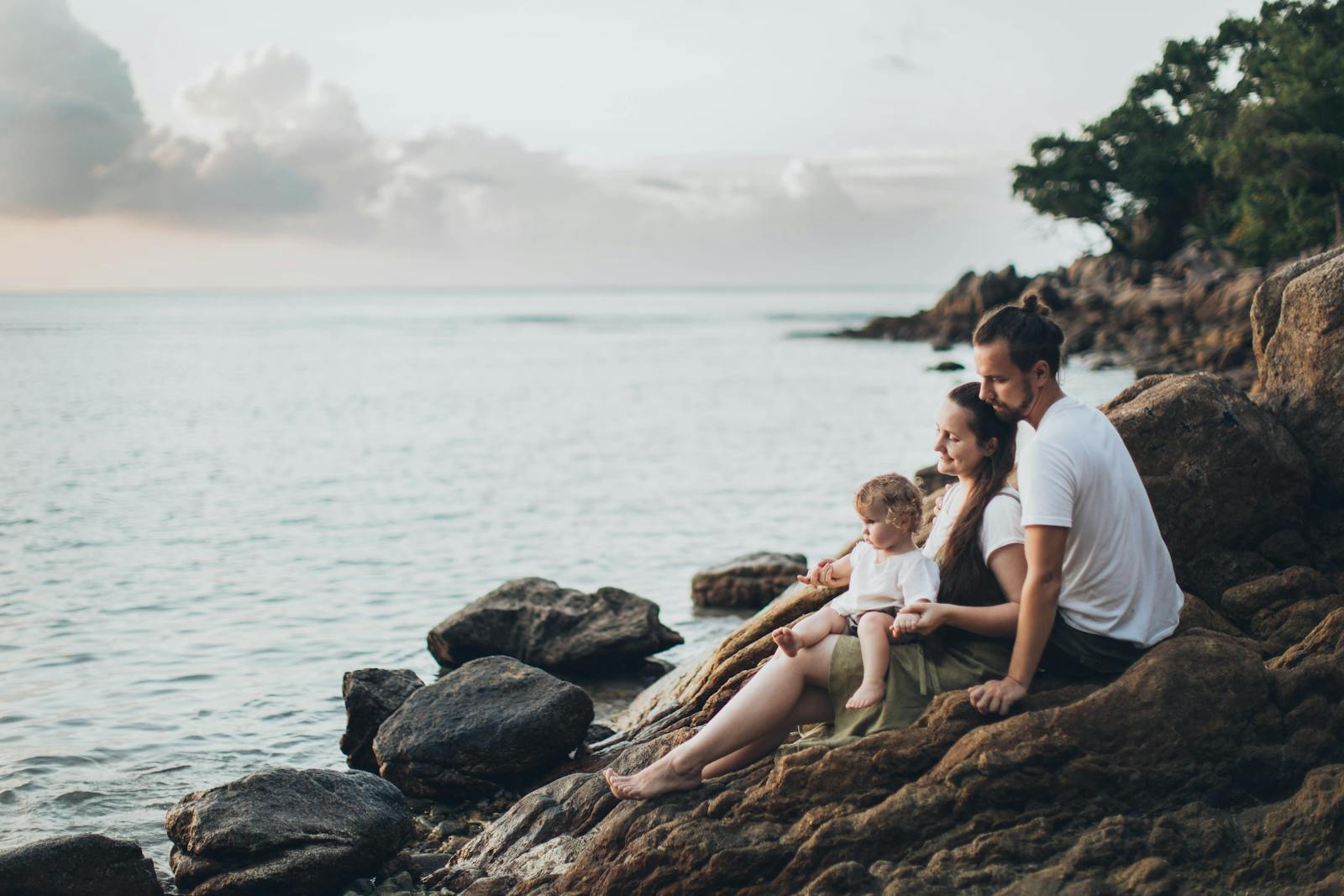 A serene family moment by the seaside, capturing love and relaxation at sunset.