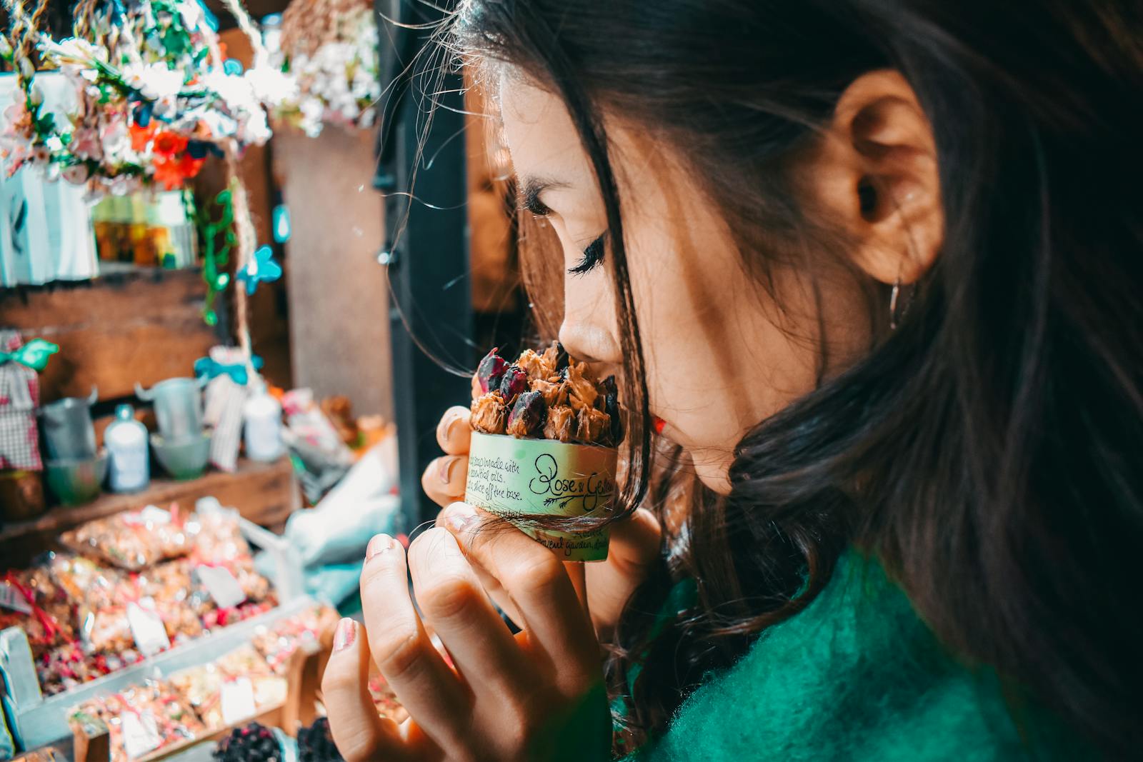 A woman savoring the scent of potpourri at a vibrant London market, capturing the essence of street life.