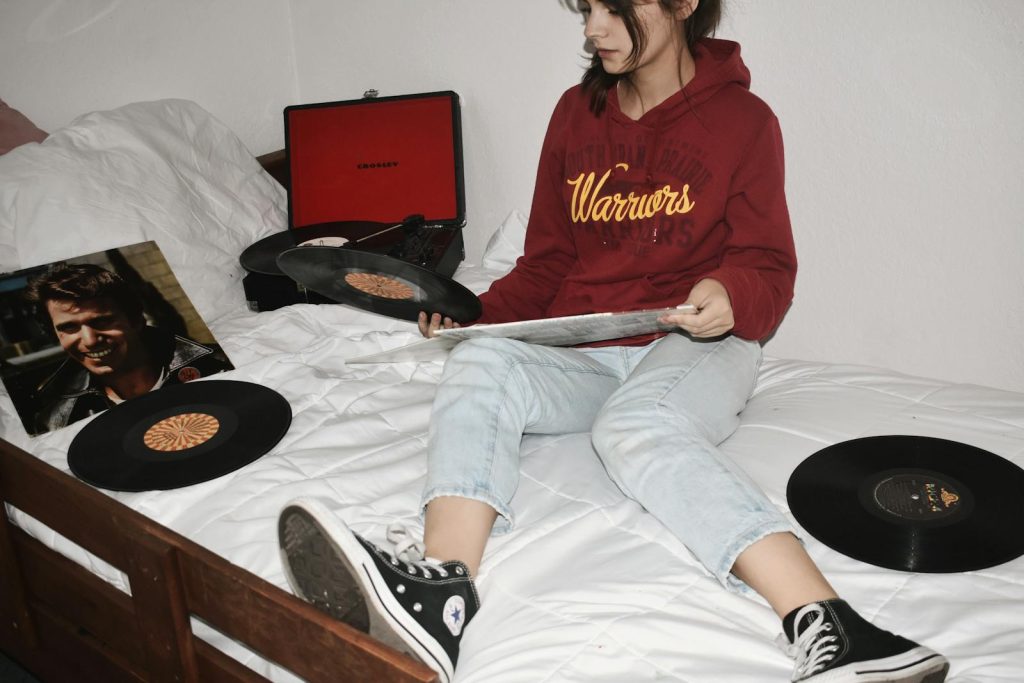 Teen girl in hoodie enjoying vinyl records in a cozy bedroom. Relaxing and vintage vibe.