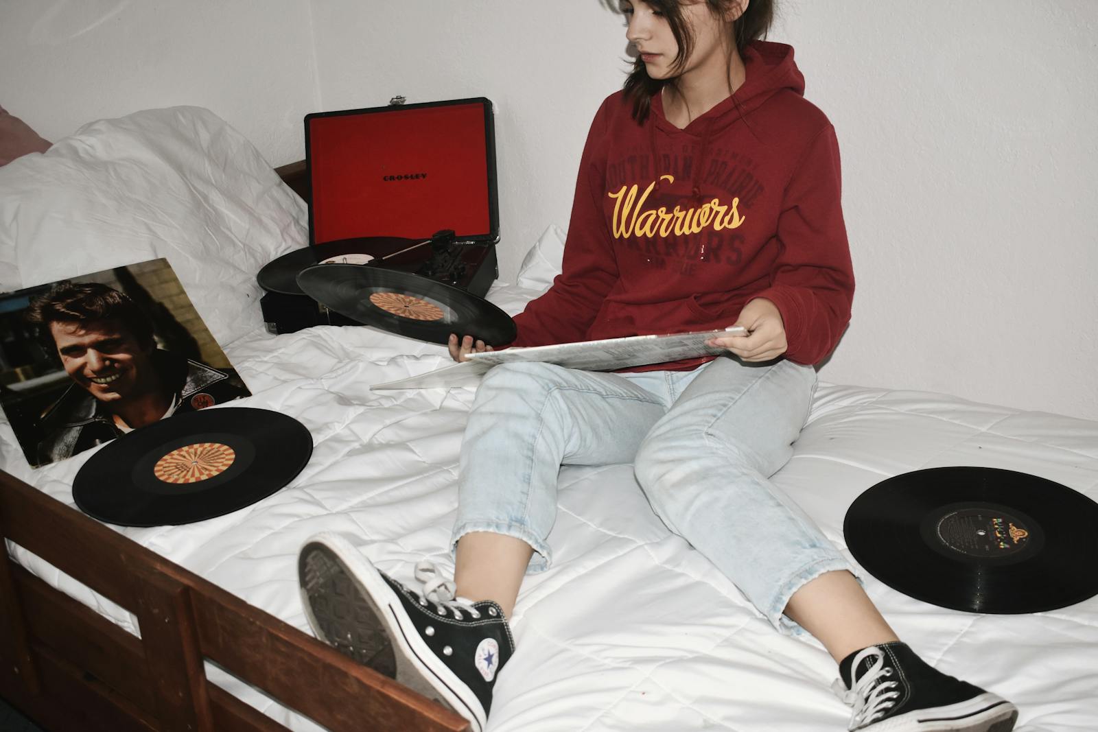 Teen girl in hoodie enjoying vinyl records in a cozy bedroom. Relaxing and vintage vibe.