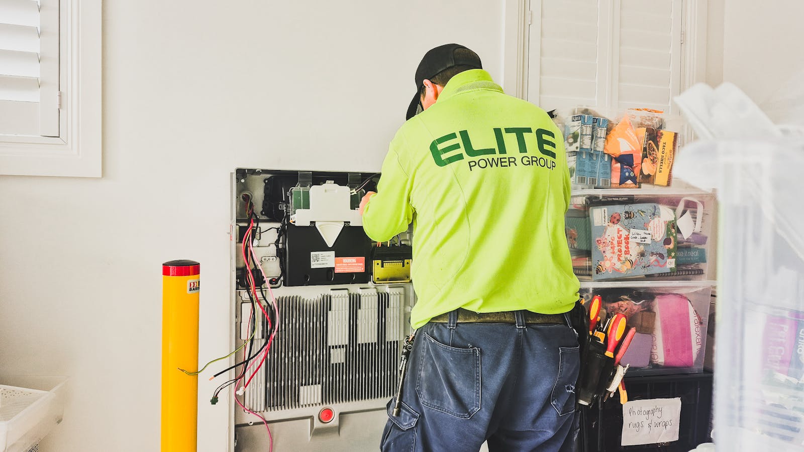 A technician from Elite Power Group installing a home battery system indoors in New South Wales, Australia.