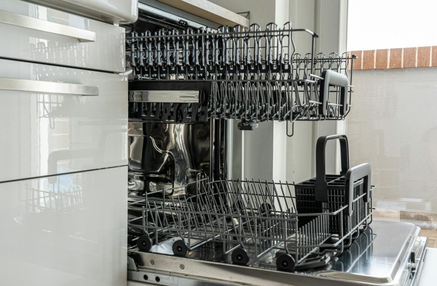 Open and empty dishwasher in a sunlit modern kitchen ready for use.