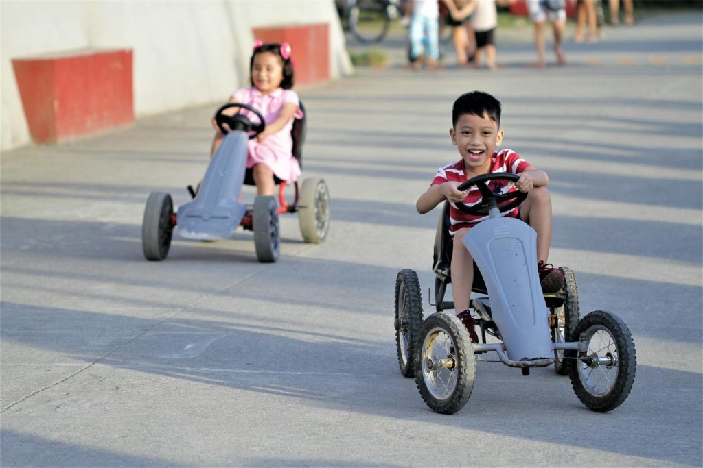 Kids joyfully riding go-karts on a sunny day in Angono, Philippines.