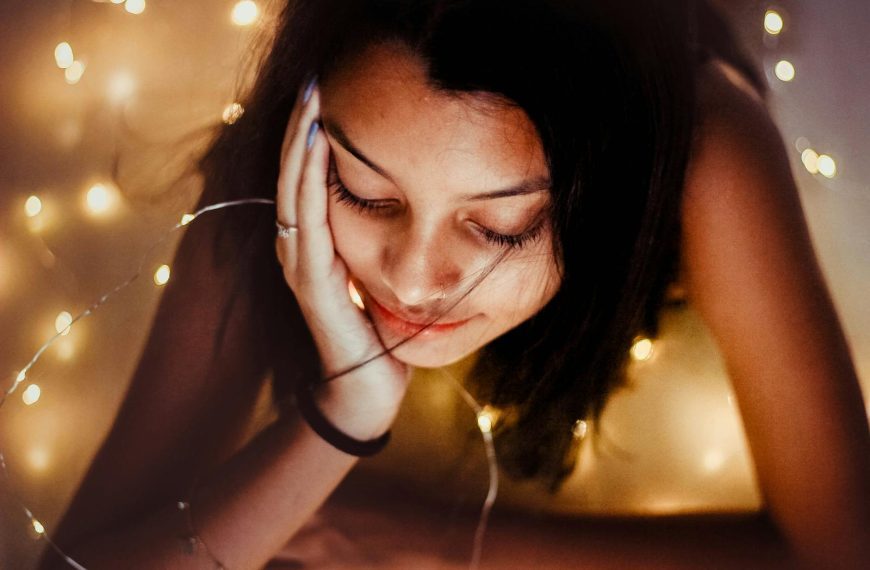 A serene portrait of a woman surrounded by glowing fairy lights, exuding warmth and tranquility.
