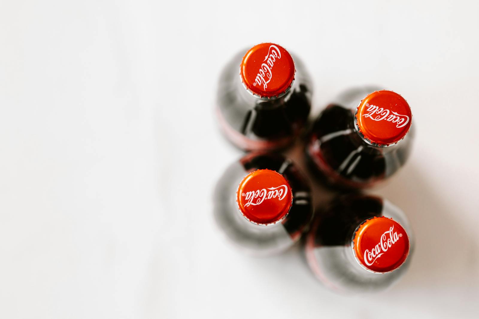 Top view of Coca-Cola bottles on a white background, focusing on branding and composition.