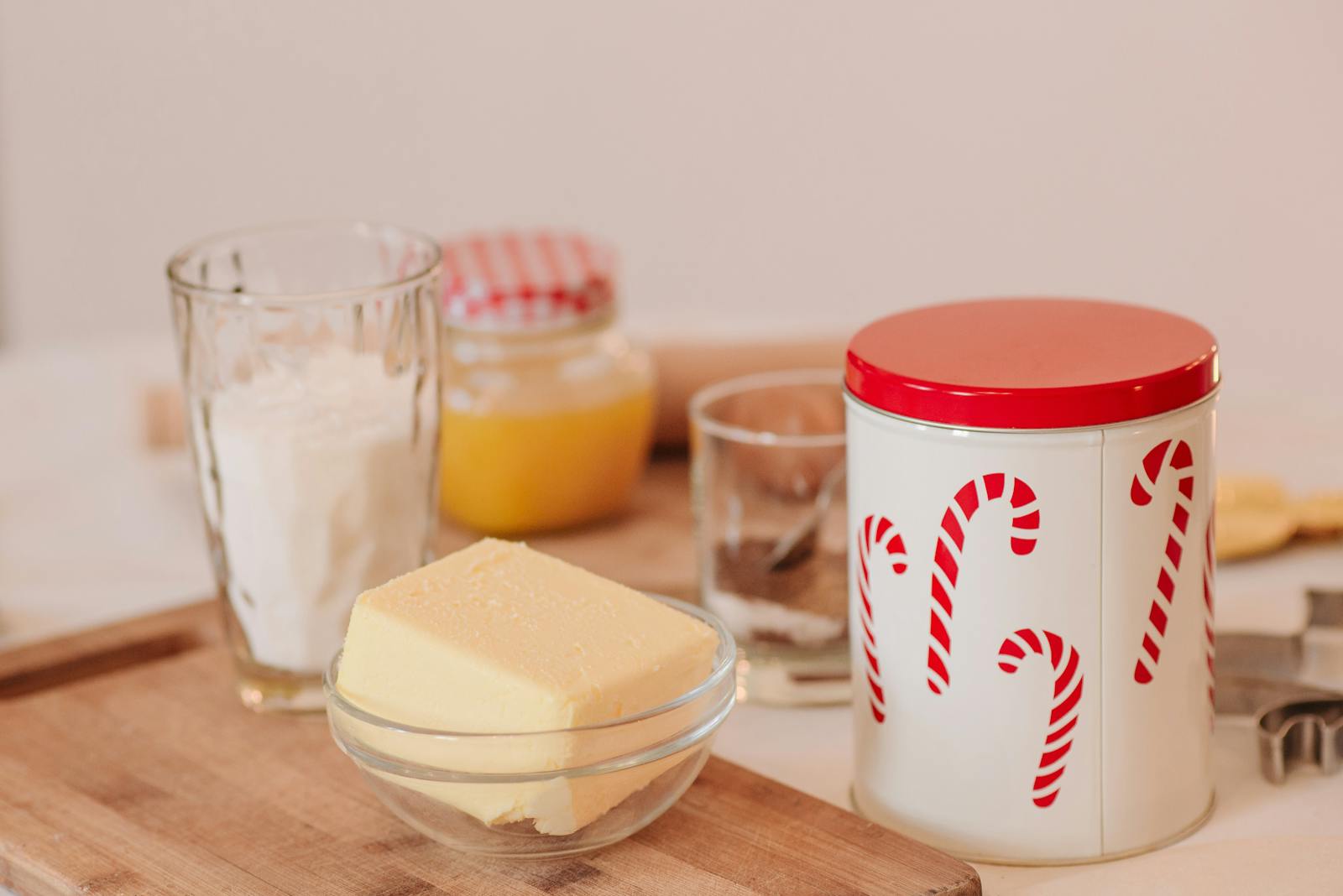 A cozy setup for holiday baking featuring butter, flour, and festive candy cane jars.